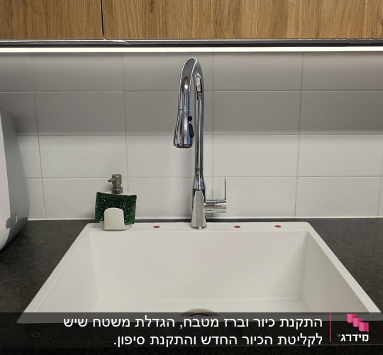 משטח שיש כהה במטבח עם כיור לבן מותקן וברז נירוסטה